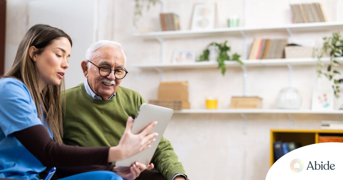 Telehealth and Senior Care Home caregiver assisting senior man to use telehealth and senior care